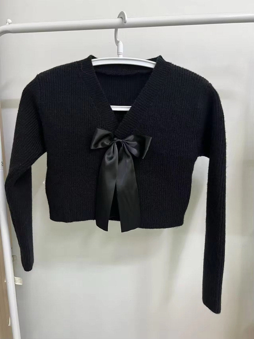 Black cropped sweater with a bow tie on a white rack