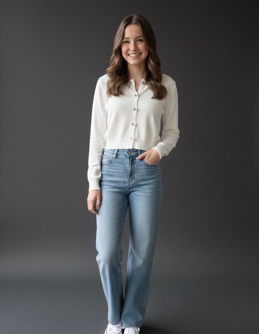 Woman wearing a white shirt and blue jeans against a dark background