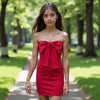 Woman wearing a red strapless dress with a large bow in a park setting
